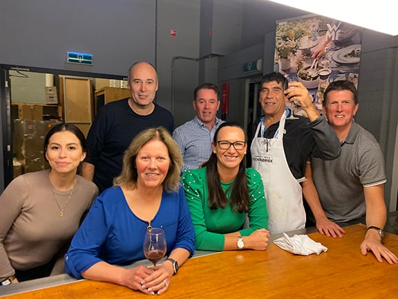 2022 Distributor Meeting in Amsterdam. Group of employees posing for a photo after cooking their dinner. 