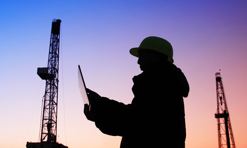 Person at an oil field at dusk reviewing viscosity data